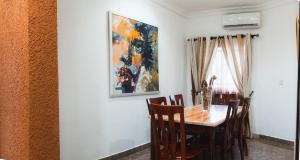 a dining room table with chairs and a painting on the wall at Spacious 3-Bedroom in Central Ikeja in Ikeja