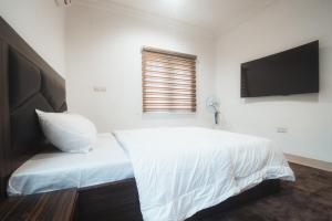 a bedroom with a white bed and a flat screen tv at Spacious 3-Bedroom in Central Ikeja in Ikeja