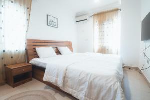 a bedroom with a bed with white sheets and a television at Spacious 3-Bedroom in Central Ikeja in Ikeja