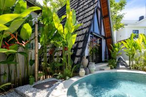 a swimming pool in a garden with plants at Brisa Lofts Uluwatu in Uluwatu
