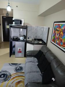 a living room with a leather couch and a kitchen at Josephine's place at Avida Aspira Tower 2 CDO in Cagayan de Oro