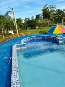 a pool with a colorful umbrella and a table with at El Atardecer in Lunarejo +22 photos