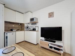 a living room with a large television and a kitchen at Cocon Cosy in Carnon-Plage