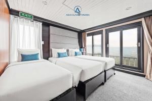 two beds in a room with a view of the ocean at Aqua Classic Cruise in Ha Long
