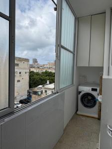 a laundry room with a window and a washing machine at Cringe Boutique APT in Netanya