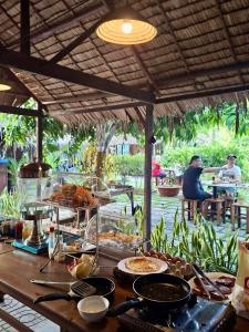 a table with food on it with people sitting at tables at Muong Dinh Lodge in Ấp Nhơn Bình