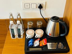 a tea kettle and cups of coffee on a tray at Arth Suites Lucknow Gomti Nagar in Lucknow