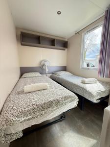 two beds in a room with a window at Le G9 - Bungalow lumineux pour 4 avec TV in Boofzheim