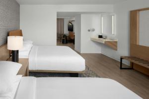 a hotel room with two beds and a desk at Sheraton Suites Fort Lauderdale at Cypress Creek in Fort Lauderdale +28 photos
