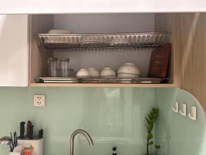 a kitchen shelf with dishes and a sink in a kitchen at Homestay Nhà Thu Thu Vinhome Ocean Park in Gia Lâm Pho