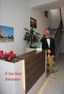 a man in a tuxedo is standing behind a counter at Fortuna Guest House - Charm & Relax rooms in Syracuse