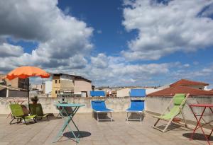 a patio with chairs and a table and an umbrella at Fortuna Guest House - Charm & Relax rooms in Syracuse