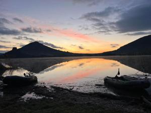 two boats sitting on the shore of a lake at sunset at Les Jasmins de Salelles in Le Bosc