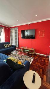 a living room with a couch and a tv on a red wall at Two Sixty Nine in Gqeberha