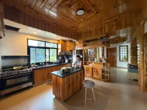 a kitchen with wooden cabinets and a woman sitting at a counter at Carpenters homestay in Sagada