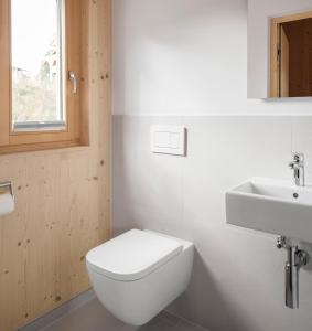 a white bathroom with a toilet and a sink at Haus Kienzerleweg in Bad Kohlgrub