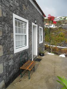 a bench sitting in front of a stone building at Adega Ilhéu in Feteira