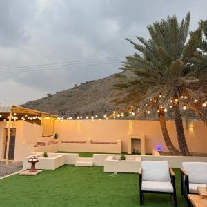 a patio with white furniture and a palm tree at safeer farm in Qūr