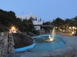 a pool with a waterfall in a resort at night at Armonia by Grispos Villas in Schinoussa