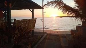 ein Sonnenuntergang über dem Meer mit einer Bank am Strand in der Unterkunft CLM Beach Resort in Medellin
