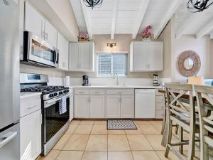 a kitchen with white cabinets and a stove top oven at Oceanfront withIncredible Beach Views home in Newport Beach