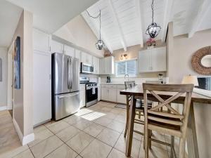 a kitchen with white cabinets and a table and a refrigerator at Oceanfront withIncredible Beach Views home in Newport Beach
