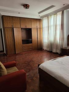 a bedroom with a bed and wooden cabinets and a couch at Aster Mekuria in Addis Ababa
