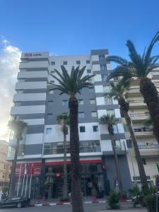 a group of palm trees in front of a building at cozy Apartment, Parc Serenity in Mohammedia
