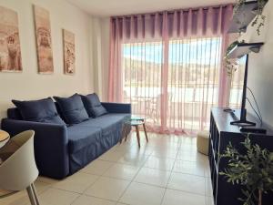 a living room with a blue couch and a large window at Belice 1-6 in Lloret de Mar