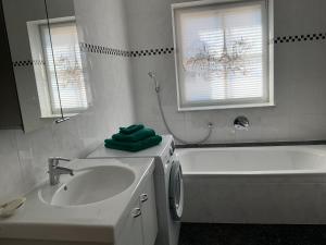 a white bathroom with a sink and a tub at See & Natur Apartment Uffing in Uffing +9 photos