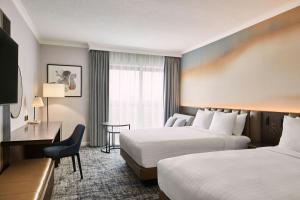 a hotel room with two beds and a desk at London Marriott Hotel Marble Arch in London