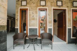 a porch with three chairs and a table and a door at Santhi Graha Guest House in Legian