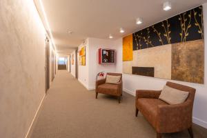 a hallway with two chairs and paintings on the walls at Hotel Centrale in Cernobbio