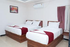 two beds in a hotel room with white and red sheets at THE RAMA Executive in Tuljapur