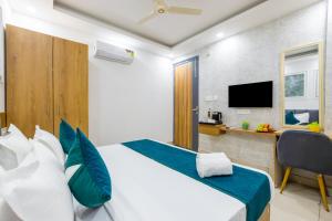 a bedroom with a bed and a desk with a television at Fortune Inn Sector - 104 By ASPL in Noida
