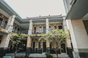 an old building with trees in the courtyard at Santhi Graha Guest House in Legian