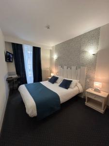 a hotel room with a large bed with blue pillows at Hôtel Le Centre in Les Herbiers +15 photos