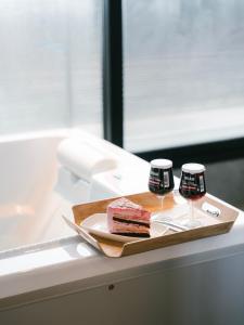 a tray with a piece of cake and two wine glasses at Hotel Parangvue in Goseong