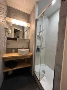 a bathroom with a sink and a shower at Hôtel Le Centre in Les Herbiers