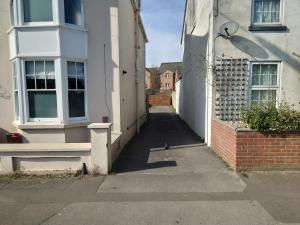 an alleyway between two white buildings with a street at Basin Road 2 Bed House in Chichester