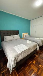 two beds in a bedroom with blue walls and wooden floors at One Thirty Six in Gqeberha