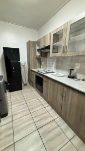 a kitchen with wooden cabinets and a black refrigerator at One Thirty Six in Gqeberha