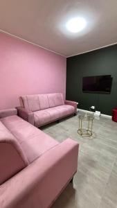 a living room with pink furniture and a flat screen tv at One Thirty Six in Gqeberha