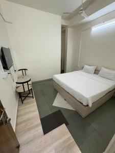 a bedroom with a white bed and a table and a tv at Ghate rooms in Nagpur +69 photos