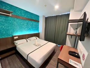 a room with a bed and a desk and a television at Smile Hotel Cheras Pudu KL in Kuala Lumpur