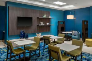 a waiting room with tables and chairs and a flat screen tv at Courtyard Miami Beach South Beach in Miami Beach