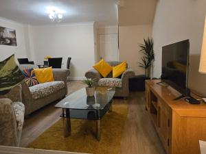 a living room with a couch and a tv at The Flexible Lodge-Ashford in Kingsnorth