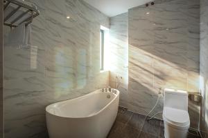 a bathroom with a white tub and a toilet at Dan Thanh Hotel in Can Tho