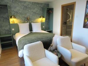 a bedroom with a large bed with two chairs at Le Foyer Celtique in Ploërmel
