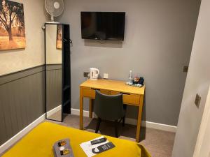 a room with a desk with a television and a chair at The Tower Arms Hotel in Iver